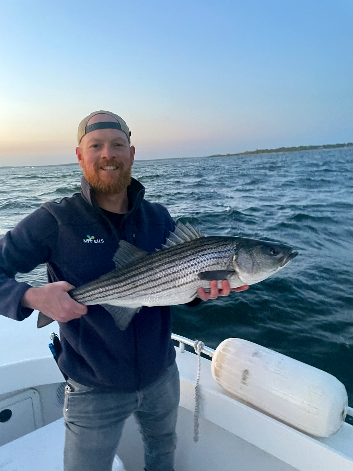 Hunter Lamere smiles and holds a large fish while standing on a boat in open water