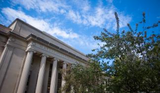 Photo of MIT Building 10, which has columns in front, as well as a tree in bloom
